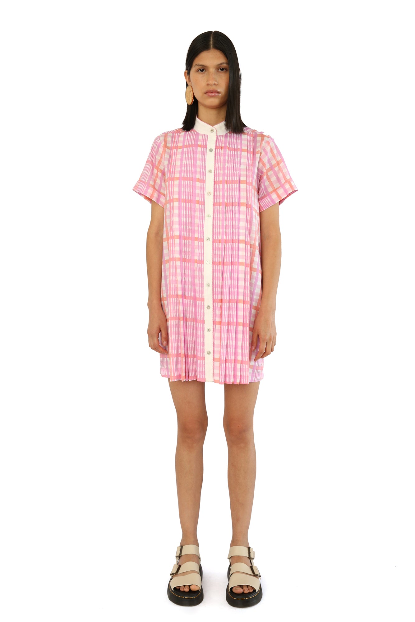 De Loreta Azulejo Dress in Loto print: Stylish mini pleated shirt dress in Loto print, featurinf a pink and lilac plaid pattern. A vibrant design with a comfortable fit. Made from high-quality cotton fabric, this versatile dress is perfect for casual and dressy occasions, offering a chic and modern look.