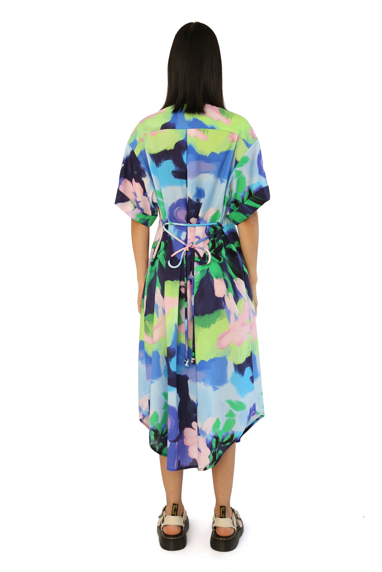 De Loreta Mari Dress in Oleo Azul print: Elegant midi shirt dress in Oleo Azul a blue, green and pink colored print, featuring a classic button-down design and a flattering silhouette. Made from high-quality fabric, this versatile dress is perfect for both casual and formal occasions, combining comfort with sophisticated style.
