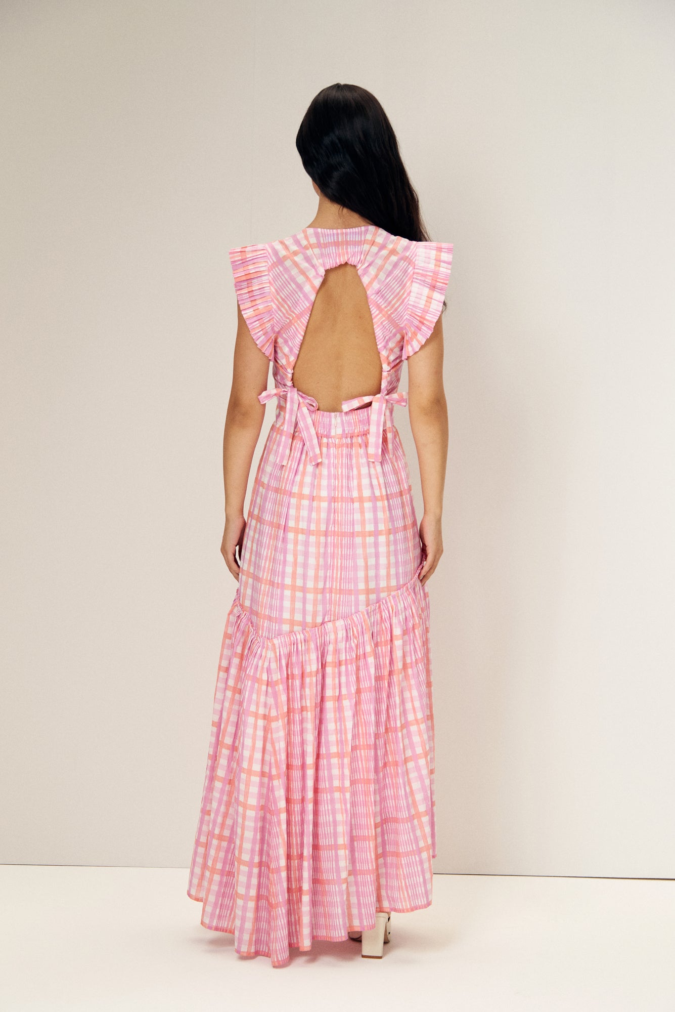 De Loreta Totora dress in Loto print: Featuring a vibrant pink and lilac plaid pattern with a flowy, asymmetric ankle-length silhouette. Designed with a flattering deep V-neckline, and a fitted bodice that flares into a breezy skirt. Crafted from soft, breathable fabric for comfort and style, perfect for summer events or casual outings