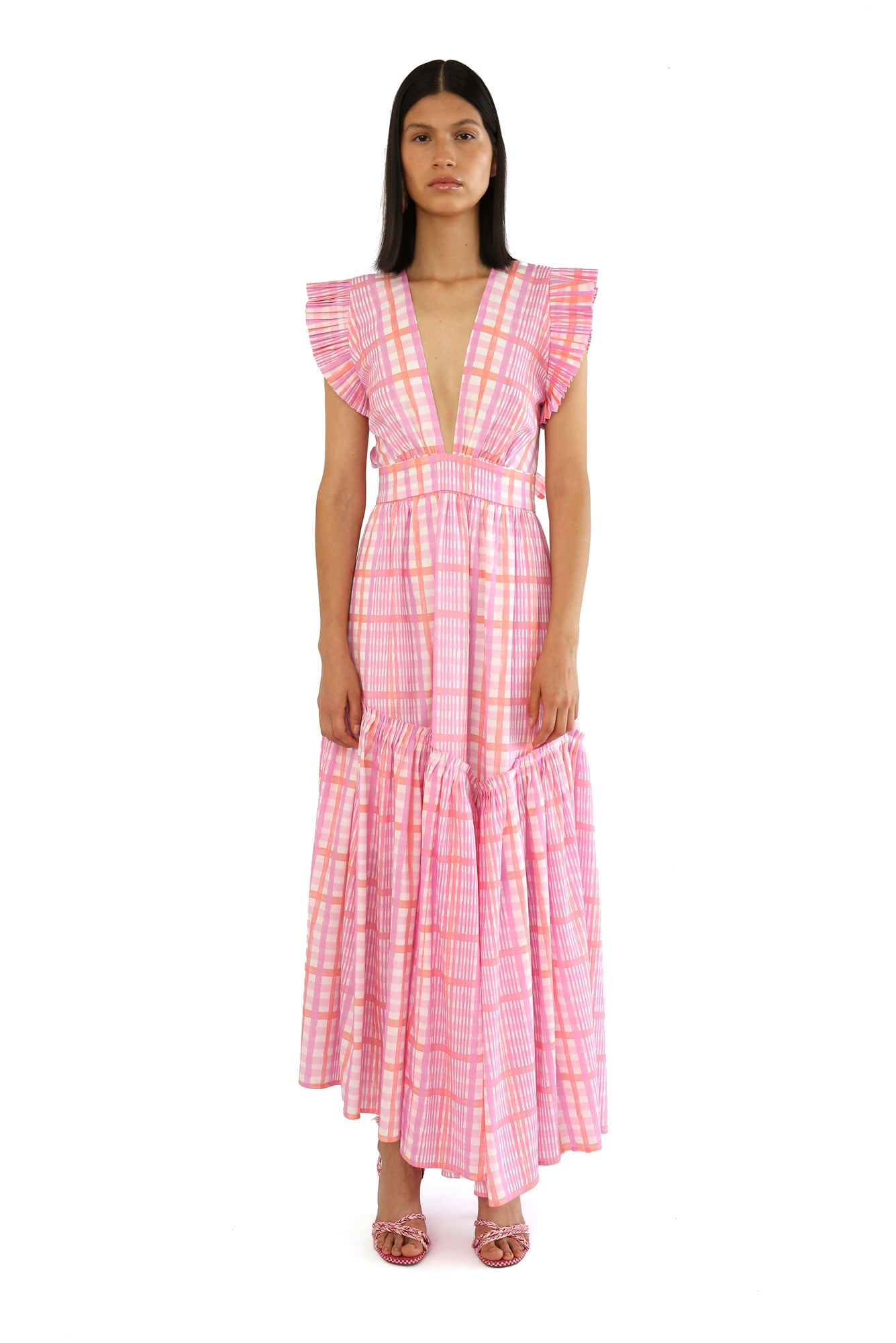 De Loreta Totora dress in Loto print: Featuring a vibrant pink and lilac plaid pattern with a flowy, asymmetric ankle-length silhouette. Designed with a flattering deep V-neckline, and a fitted bodice that flares into a breezy skirt. Crafted from soft, breathable fabric for comfort and style, perfect for summer events or casual outings