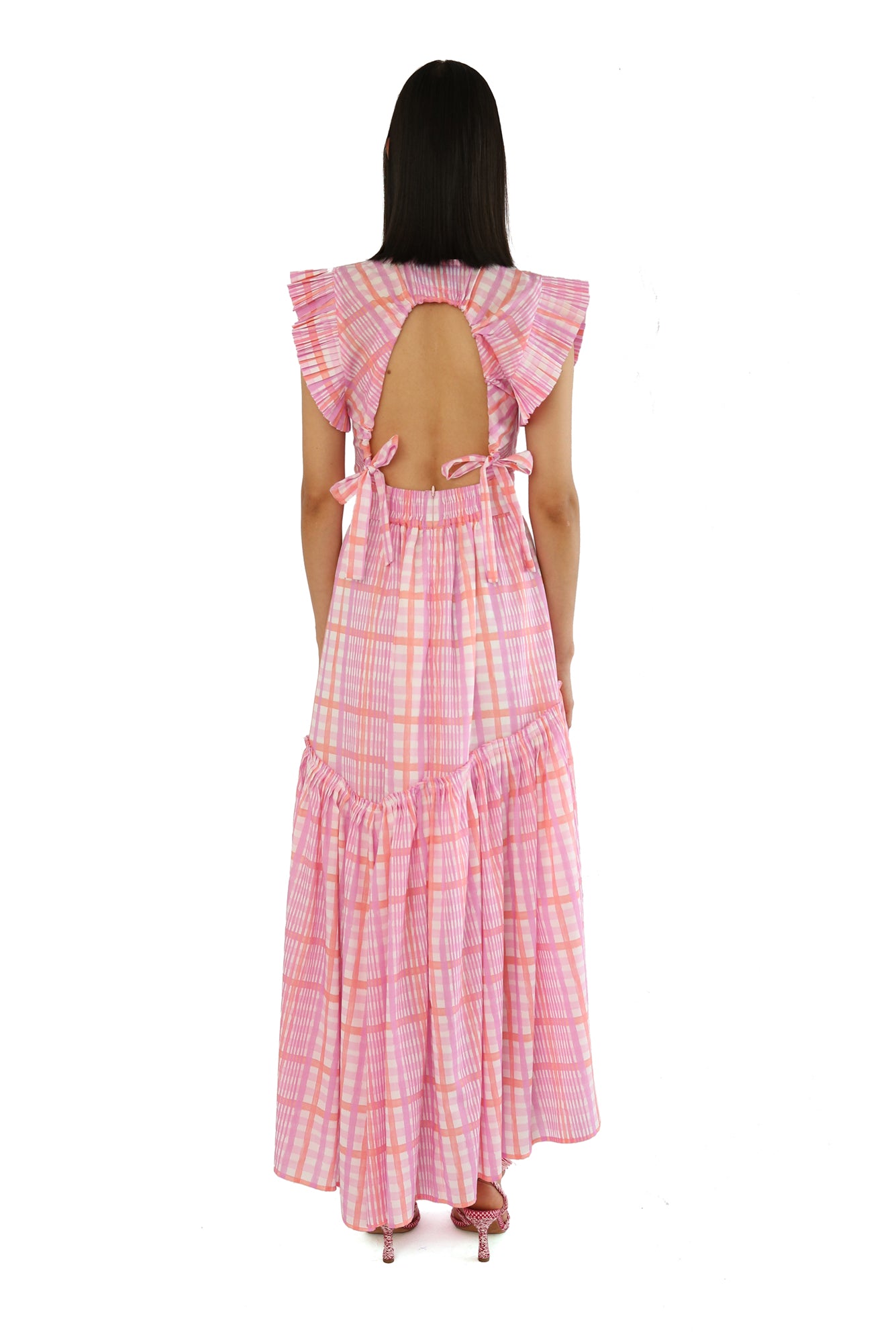De Loreta Totora dress in Loto print: Featuring a vibrant pink and lilac plaid pattern with a flowy, asymmetric ankle-length silhouette. Designed with a flattering deep V-neckline, and a fitted bodice that flares into a breezy skirt. Crafted from soft, breathable fabric for comfort and style, perfect for summer events or casual outings