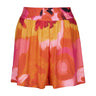 De Loreta Pachuca Shorts in Anturio Print: Vibrant Pachuca Shorts in Anturio, a red, pink and yellow colored print, featuring a stylish floral pattern and a comfortable fit. Made from high-quality fabric, these shorts are perfect for casual summer or fall wear, combining chic design with everyday comfort. Front view.